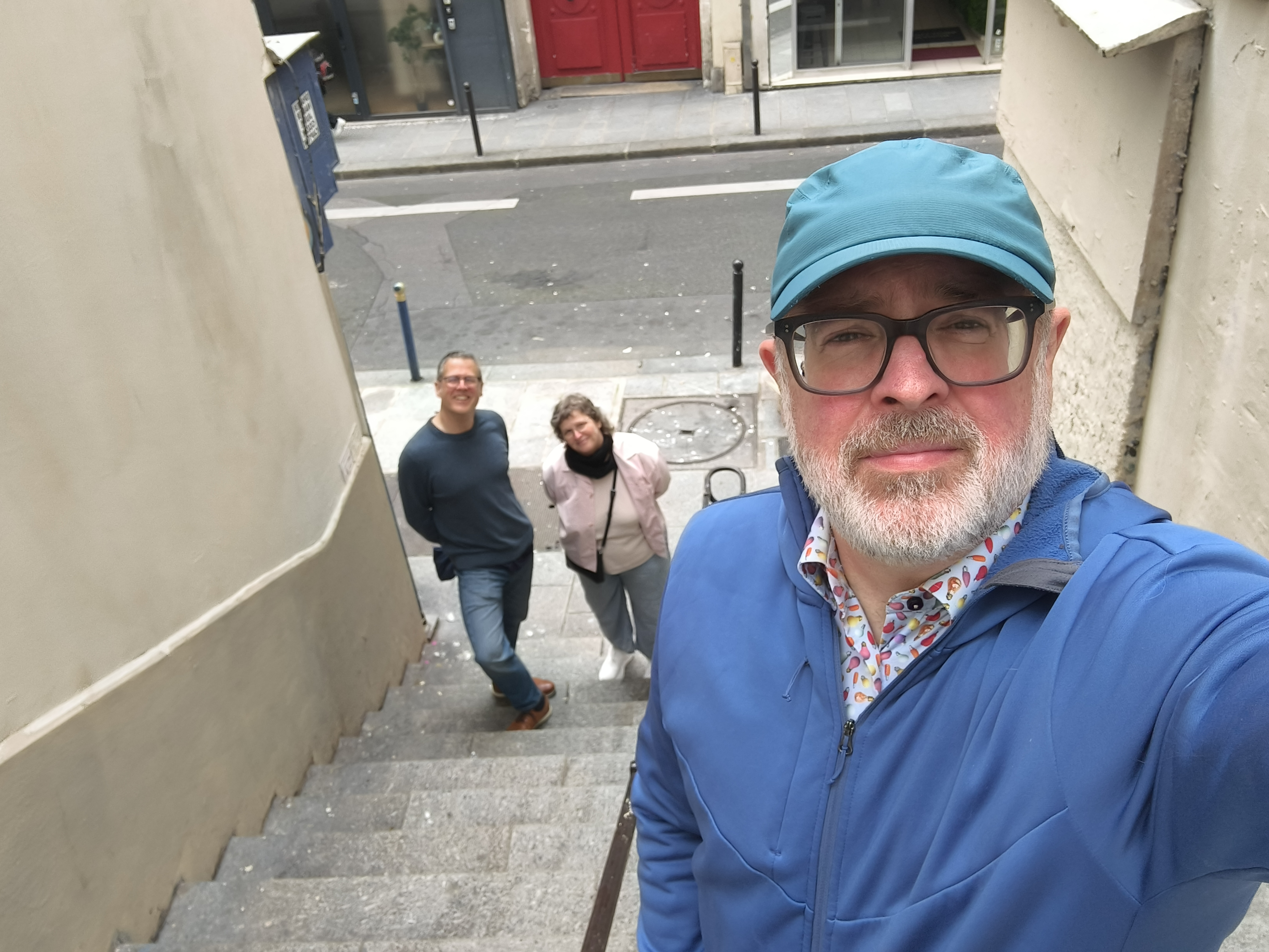 Justin Simpson with co-workers Joel and Kelly on the Rue des Degrés, the shortest street in Paris (14 steps in the 2nd arrondissement), photographed 20 May 2026